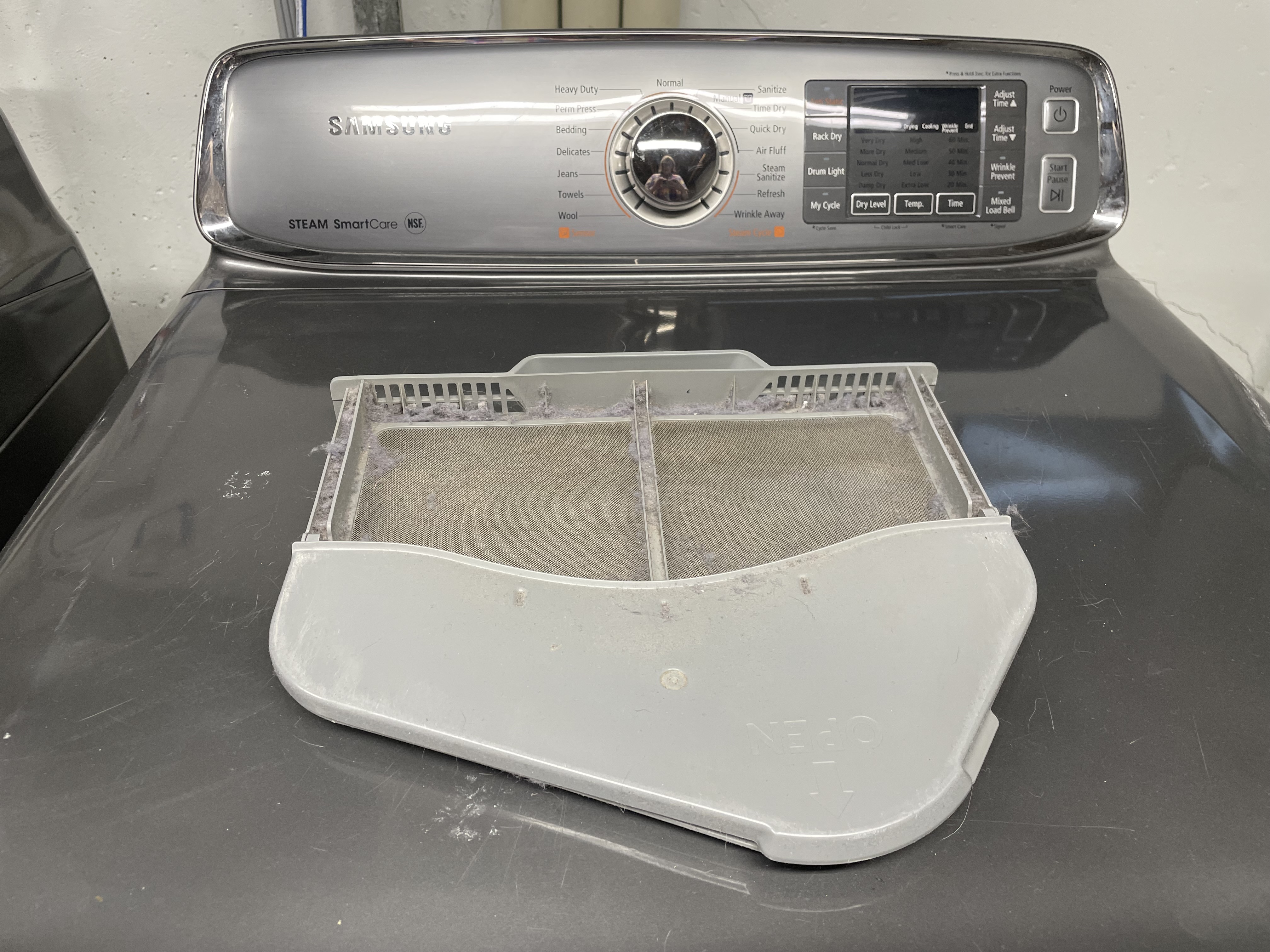 Lint trap of a dryer that has been removed and set on top of the dryer to show a clean lint trap.